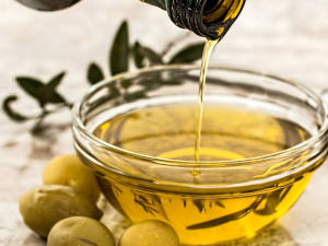 Eine Schale mit Olivenöl aus Italirn, daneben einige Oliven